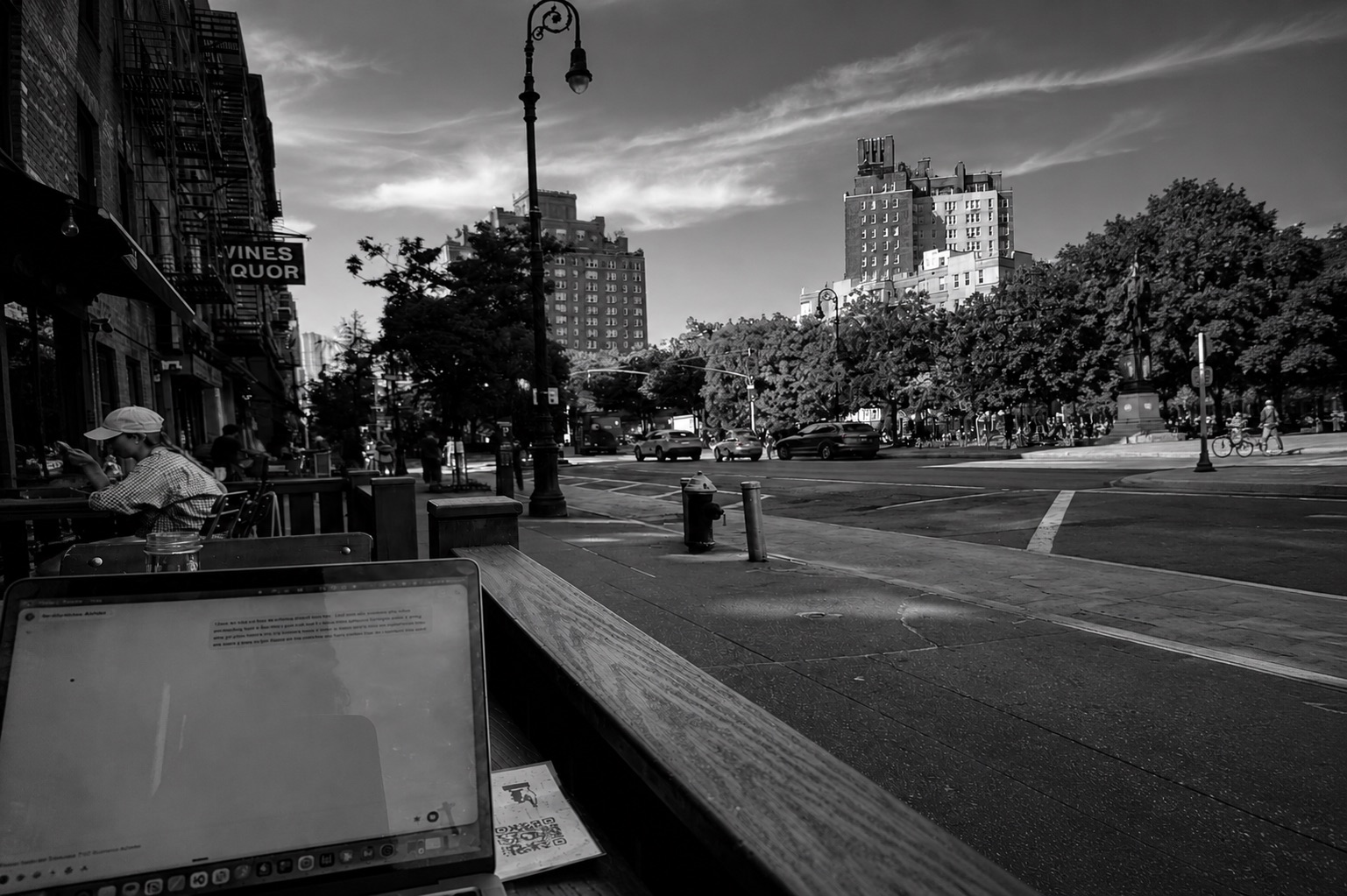 Black-and-white view over a laptop screen onto a New York City street corner