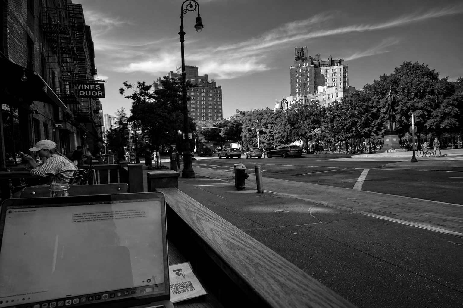 Black-and-white view over a laptop screen onto a New York City street corner
