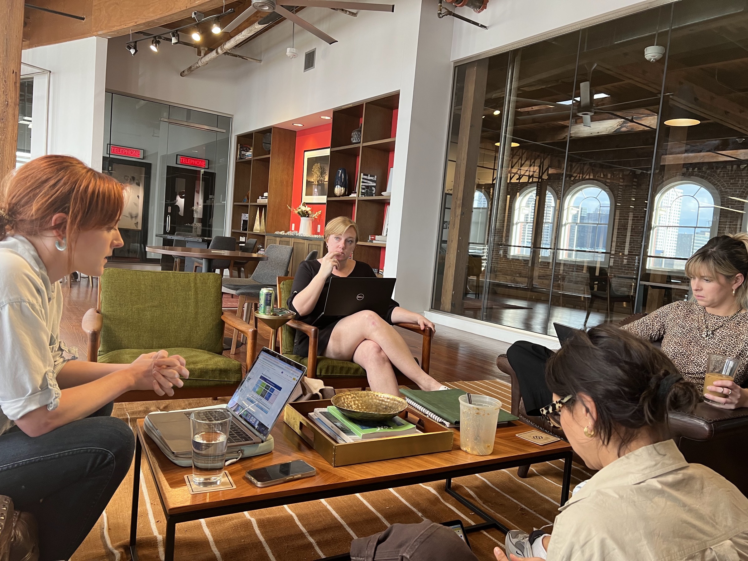 A team working session in a warehouse loft, laptops open around a low table