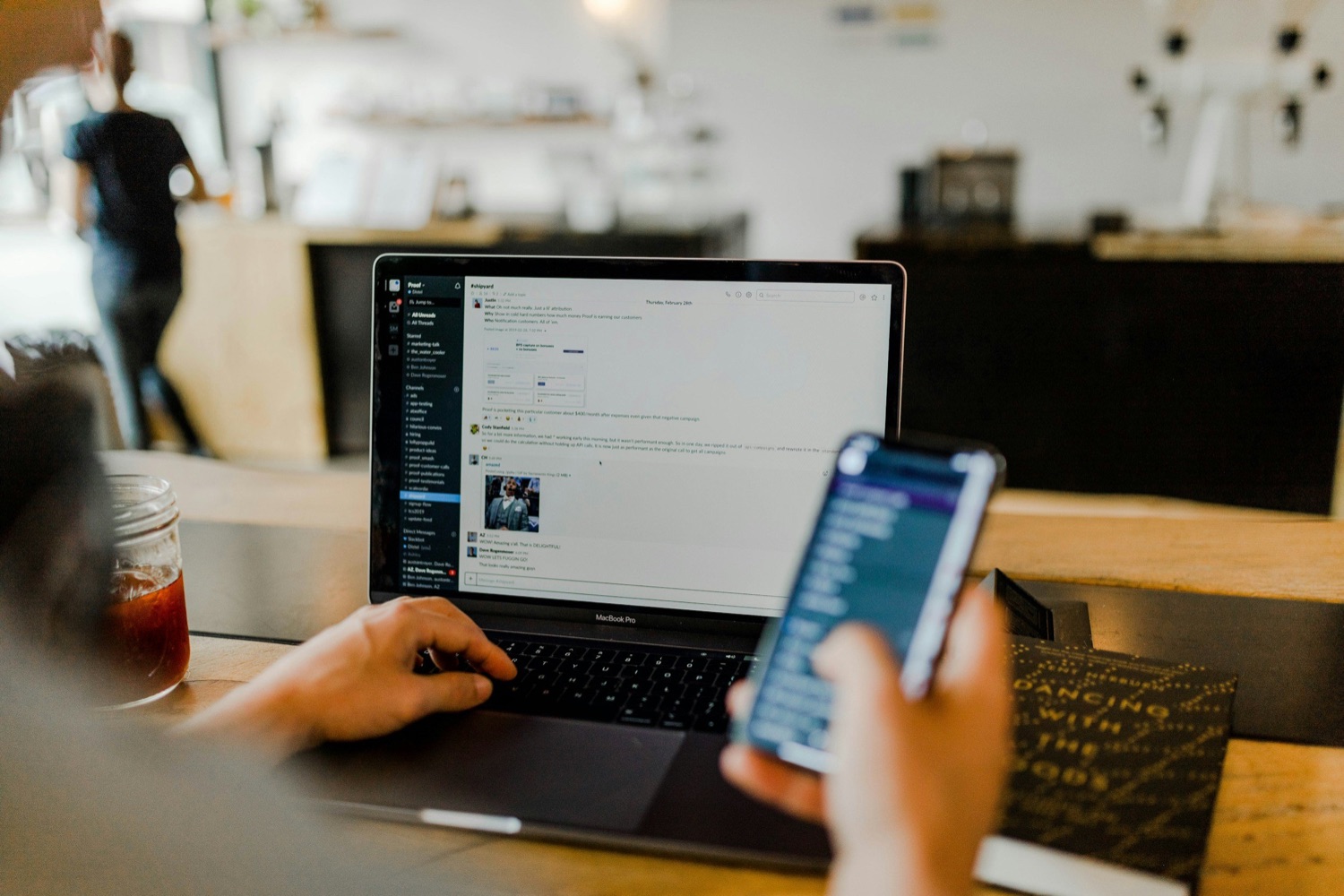 A laptop open to a team Slack workspace beside a phone