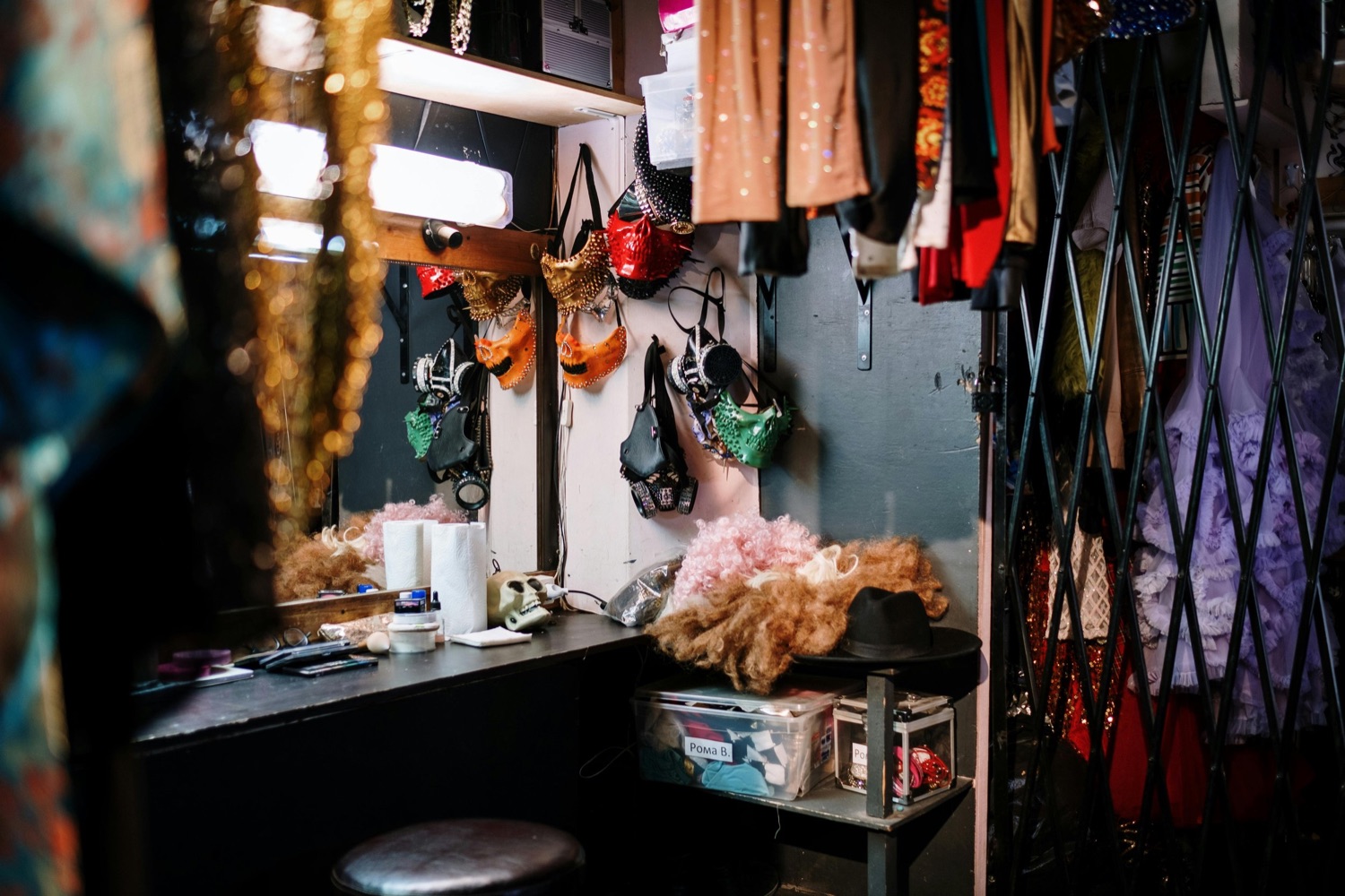 A theater dressing room backstage lined with costumes and wigs